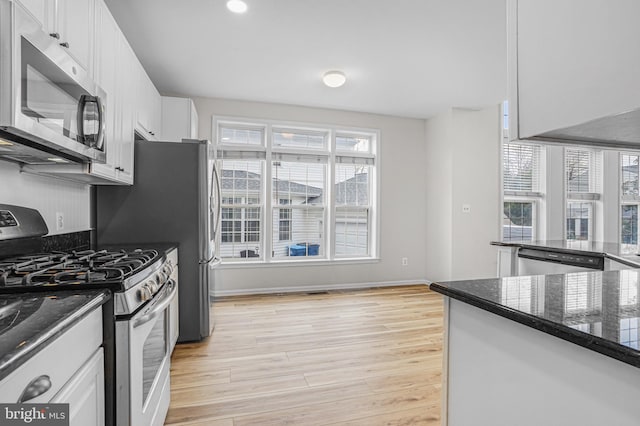 kitchen with a healthy amount of sunlight, light wood-type flooring, appliances with stainless steel finishes, and white cabinets