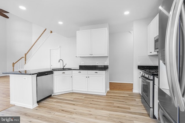 kitchen featuring appliances with stainless steel finishes, white cabinets, a sink, and a peninsula