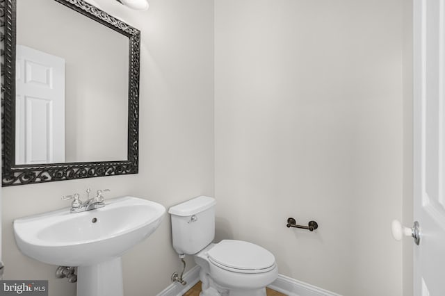 bathroom with toilet, baseboards, and a sink