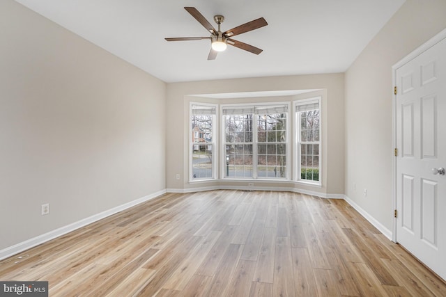 unfurnished room with light wood finished floors, a ceiling fan, and baseboards