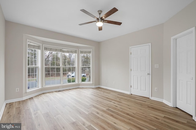 empty room with light wood finished floors, ceiling fan, and baseboards