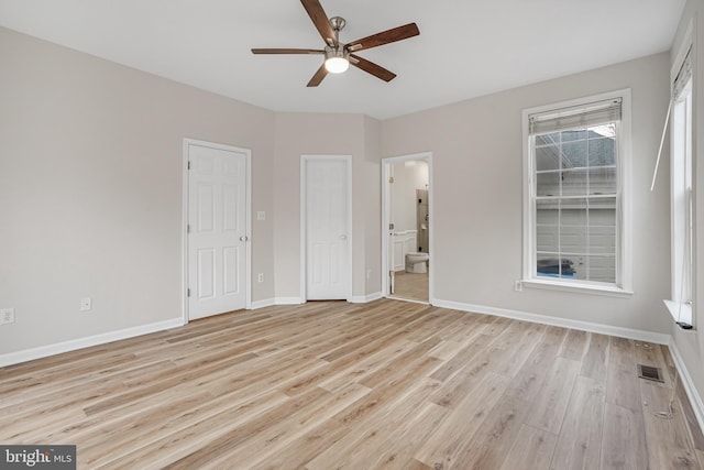 unfurnished bedroom with light wood finished floors, visible vents, baseboards, ceiling fan, and ensuite bathroom