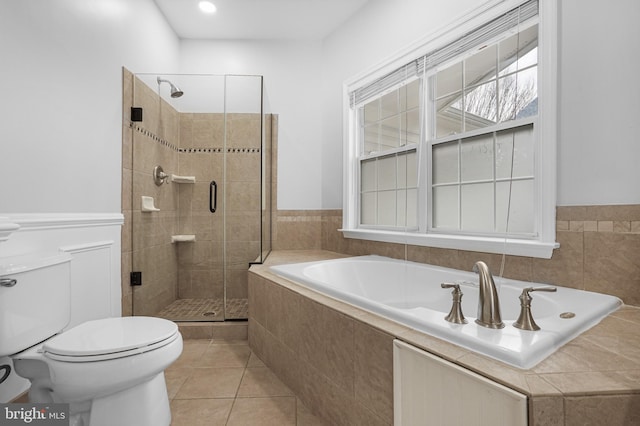 bathroom featuring a stall shower, a healthy amount of sunlight, toilet, and tile patterned floors