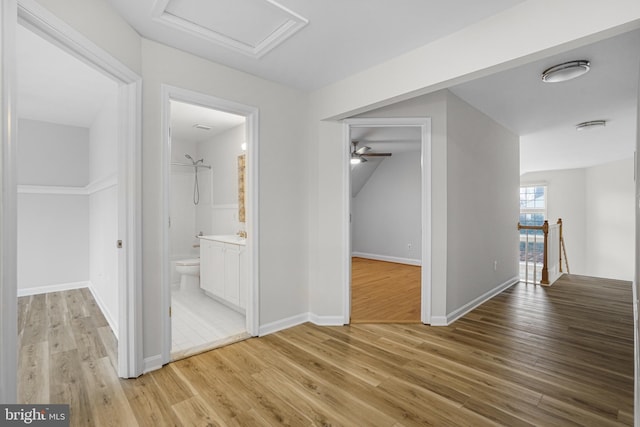 hall featuring baseboards, light wood finished floors, an upstairs landing, and attic access