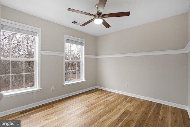 spare room featuring wood finished floors, visible vents, and baseboards