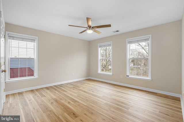 empty room with light wood-style floors, visible vents, baseboards, and ceiling fan