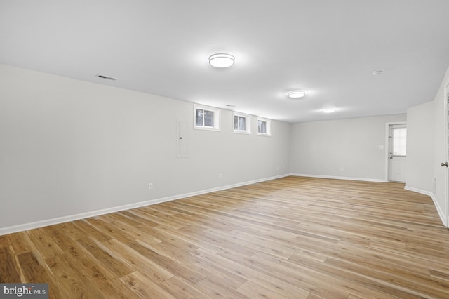 basement featuring baseboards, visible vents, and light wood-style floors