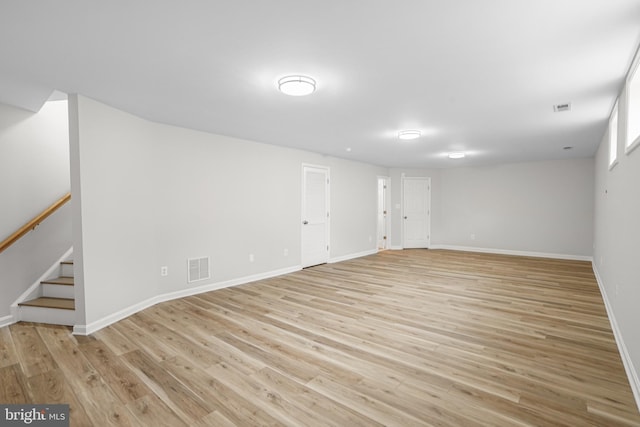 unfurnished living room featuring light wood-style flooring, stairs, visible vents, and baseboards