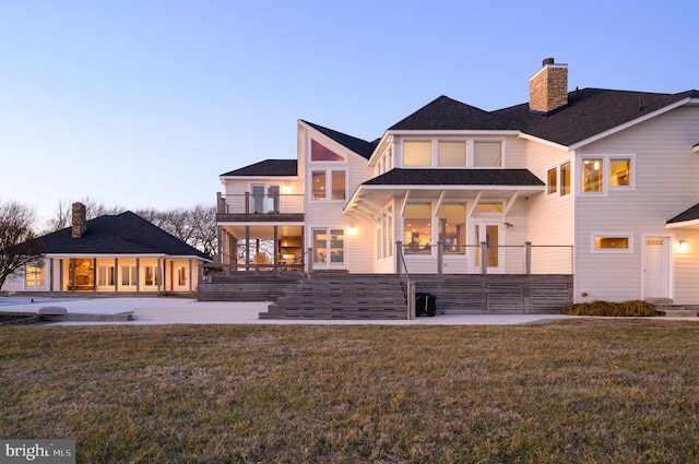 rear view of property with a patio area, a yard, a chimney, and a balcony