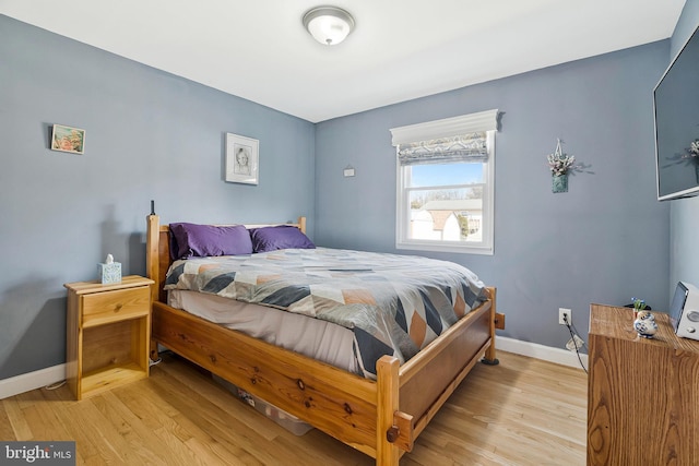 bedroom featuring light wood finished floors and baseboards