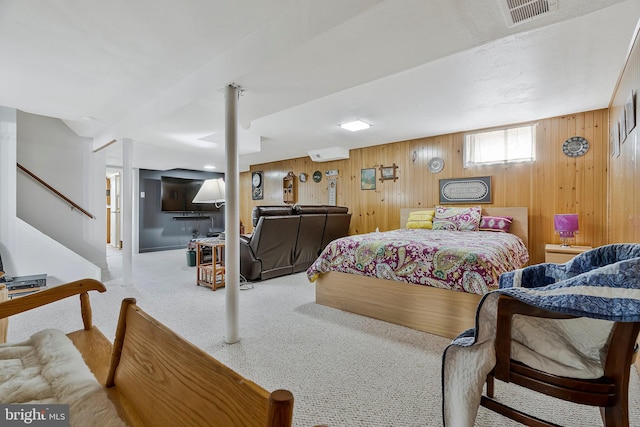 carpeted bedroom featuring wood walls, visible vents, and a wall mounted air conditioner