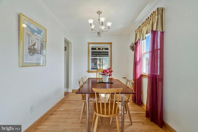 dining area with light wood-style floors, baseboards, and a notable chandelier