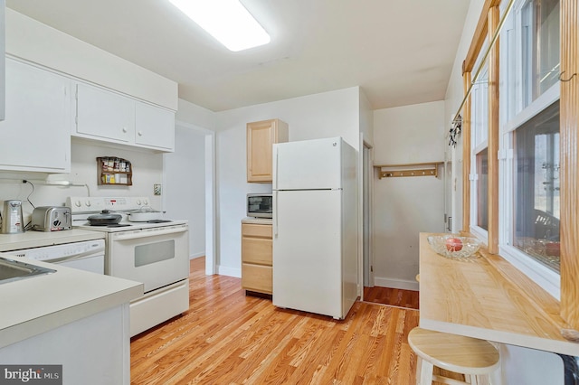 kitchen with light countertops, light wood-style floors, white cabinets, white appliances, and baseboards