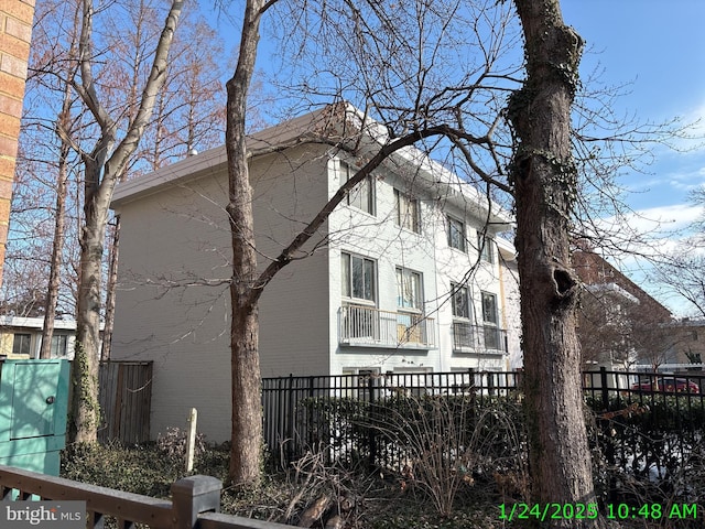 view of side of property featuring brick siding and fence