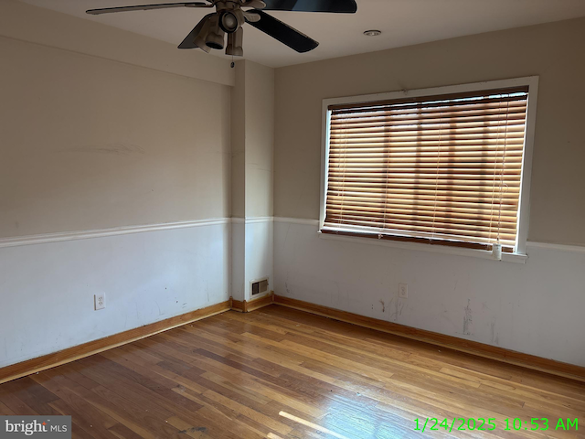 spare room featuring a ceiling fan, baseboards, visible vents, and wood finished floors