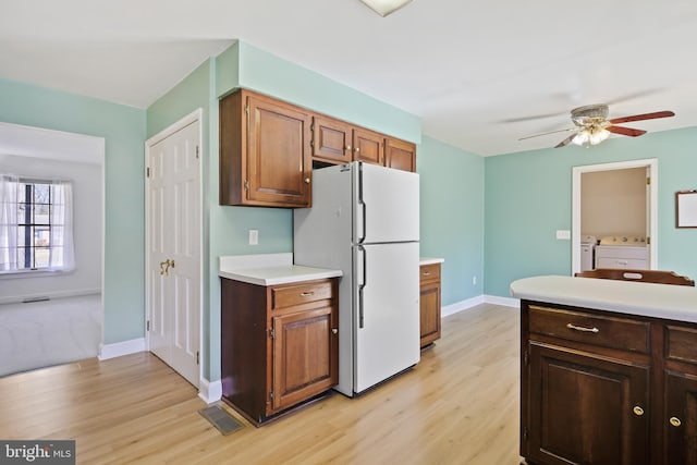 kitchen featuring light wood finished floors, visible vents, light countertops, freestanding refrigerator, and independent washer and dryer