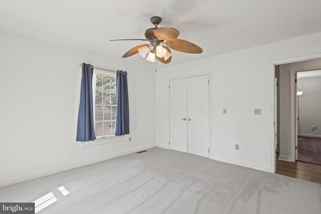 unfurnished bedroom with visible vents, a closet, carpet floors, baseboards, and ceiling fan