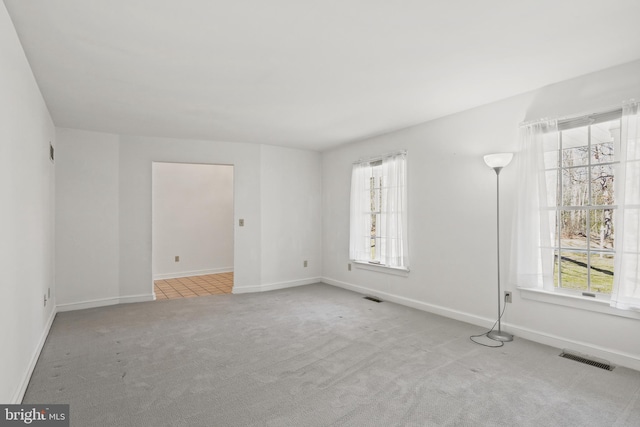 carpeted empty room with visible vents, baseboards, and a healthy amount of sunlight