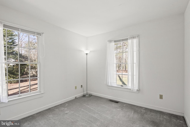 carpeted spare room featuring visible vents and baseboards