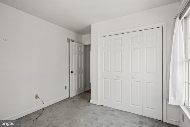 unfurnished bedroom with visible vents, carpet, a closet, and baseboards