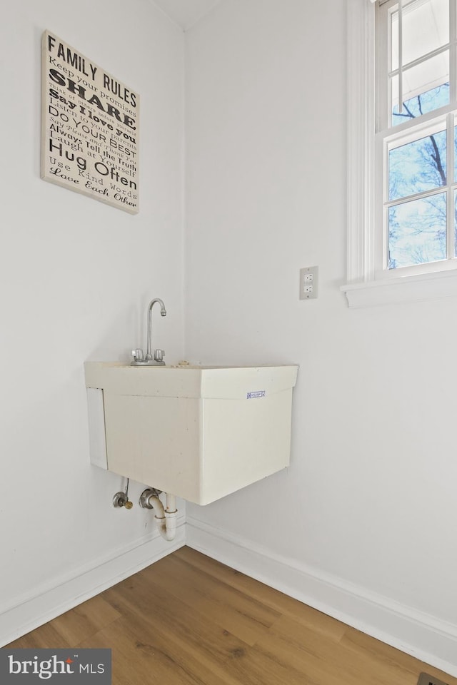 washroom featuring a sink, baseboards, and wood finished floors