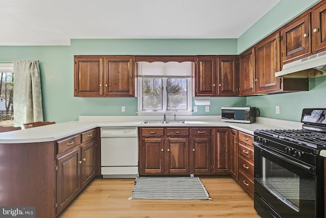 kitchen with a peninsula, under cabinet range hood, black range with gas stovetop, dishwasher, and stainless steel microwave