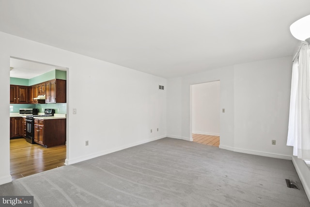 unfurnished living room featuring visible vents, baseboards, and light carpet