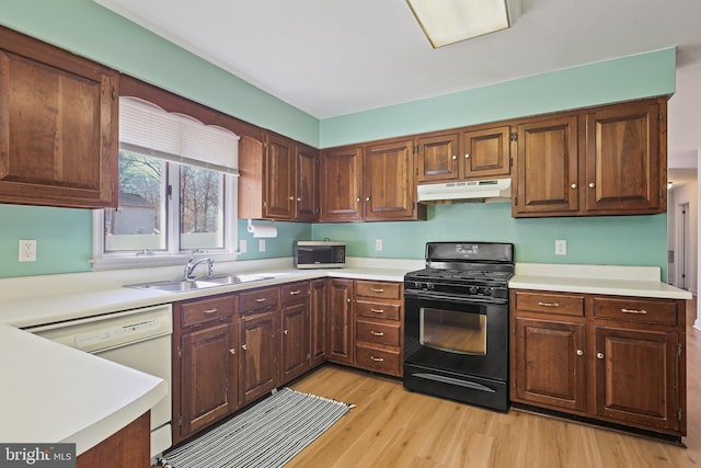 kitchen with gas stove, a sink, light countertops, under cabinet range hood, and dishwasher