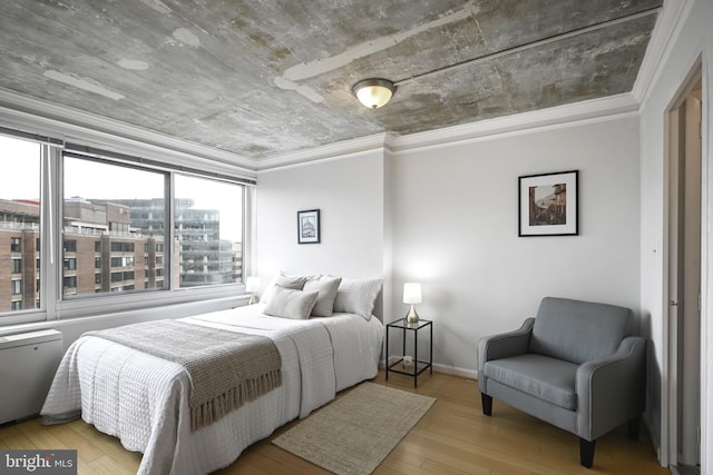 bedroom with baseboards, hardwood / wood-style floors, a view of city, and crown molding