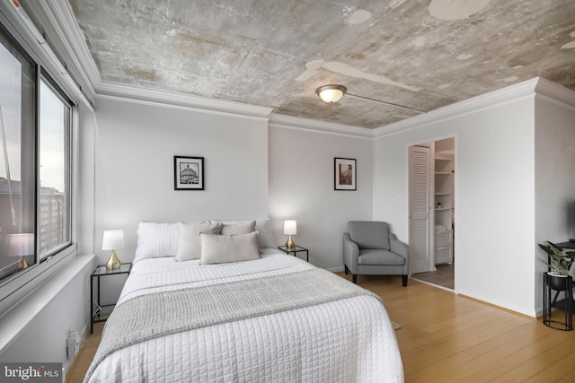 bedroom with ornamental molding, wood finished floors, and baseboards