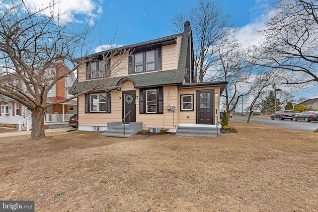 view of front of property featuring roof with shingles, a chimney, and a front lawn