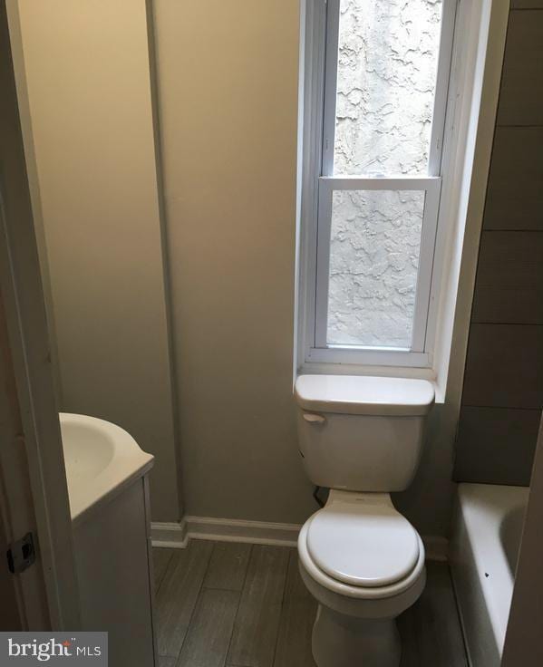 bathroom featuring toilet, wood finished floors, vanity, and a wealth of natural light