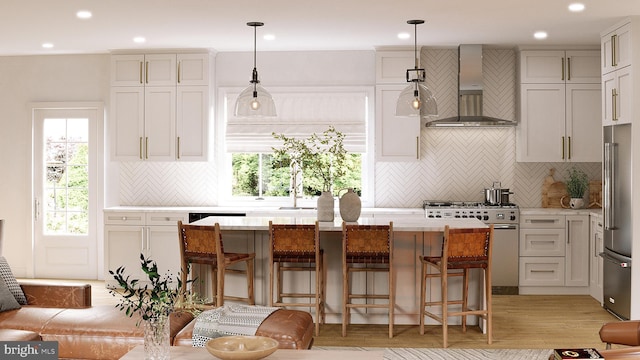 kitchen with premium appliances, wall chimney exhaust hood, a center island, light countertops, and a sink