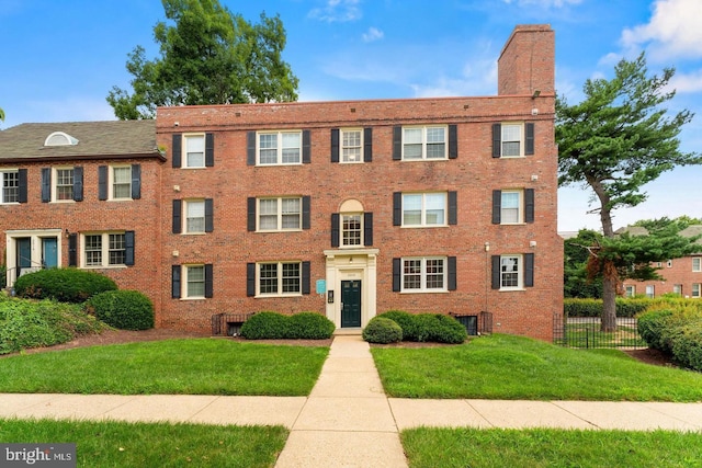 view of front of home featuring a chimney, a front yard, fence, and brick siding