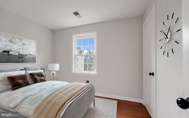 bedroom with visible vents, baseboards, and wood finished floors