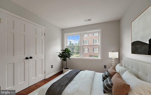 bedroom with visible vents, a closet, baseboards, and dark wood-type flooring