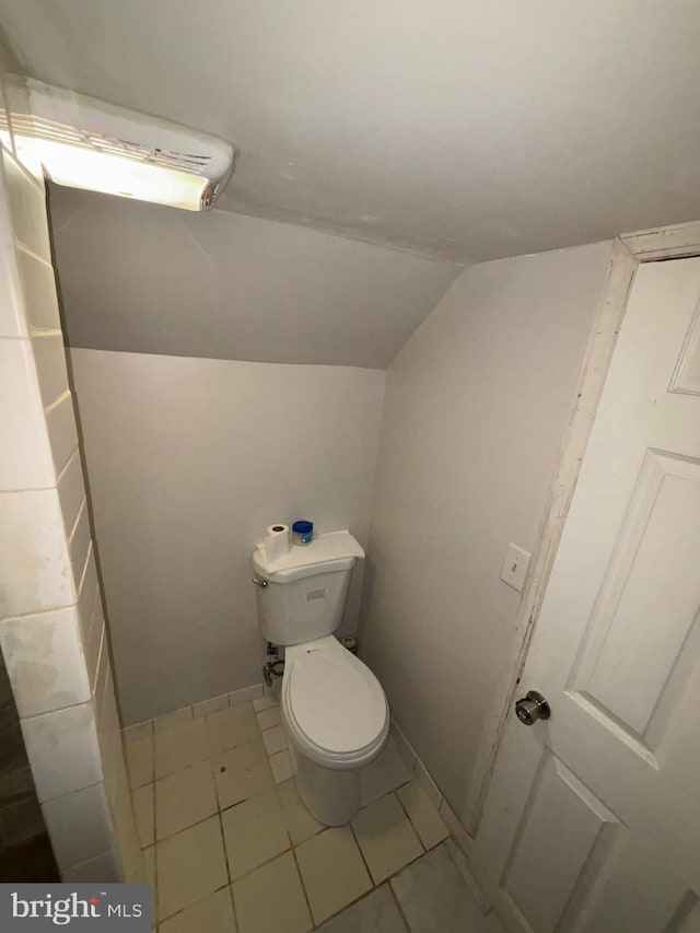 bathroom with lofted ceiling, tile patterned flooring, toilet, and baseboards