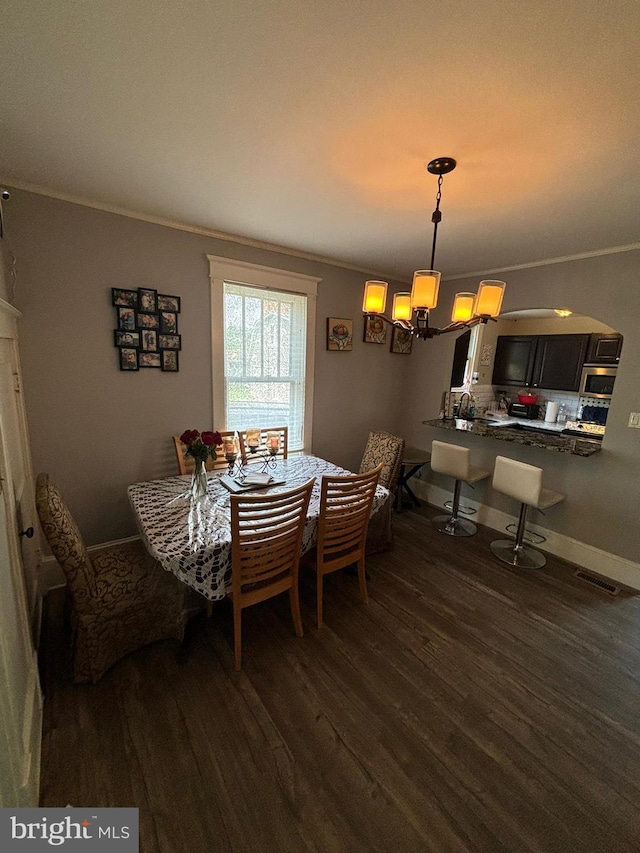 dining room featuring dark wood-type flooring, visible vents, ornamental molding, and baseboards