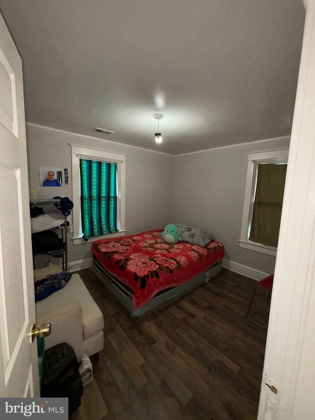 bedroom with baseboards, visible vents, and wood finished floors