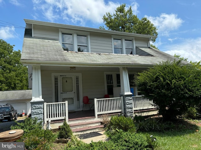 view of front facade with a garage, covered porch, and roof with shingles