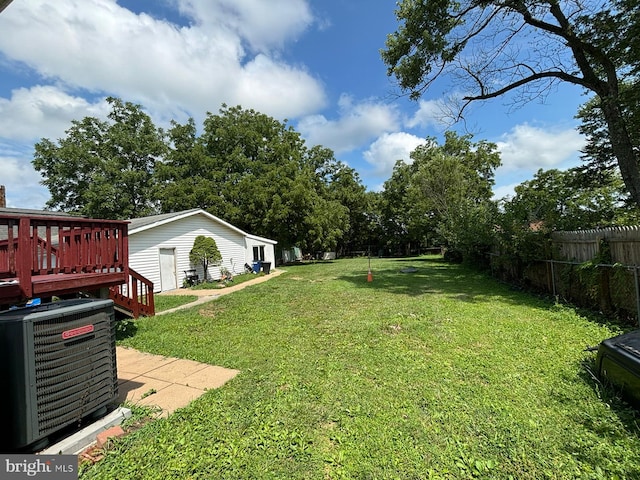 view of yard with fence, a wooden deck, and central air condition unit