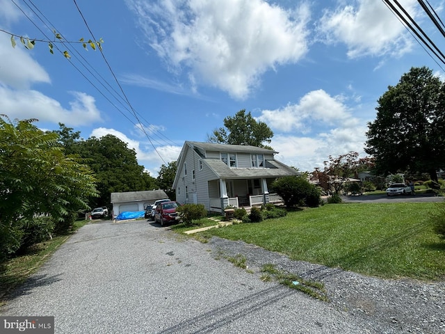 view of front of home with a porch, a front yard, and an outbuilding