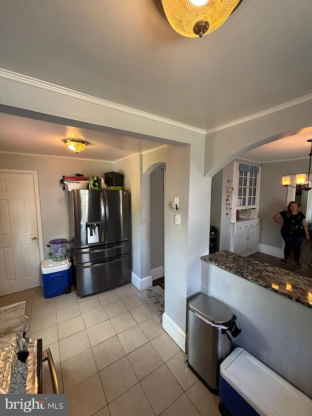 kitchen featuring ornamental molding, arched walkways, stainless steel refrigerator with ice dispenser, and light tile patterned floors