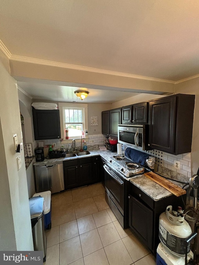 kitchen featuring light tile patterned floors, appliances with stainless steel finishes, backsplash, and a sink