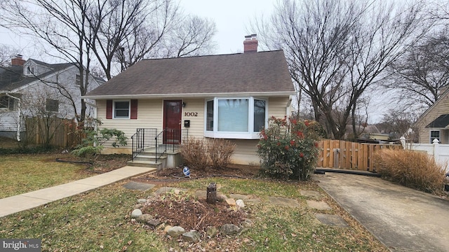 view of front of property with a shingled roof, fence, and a chimney