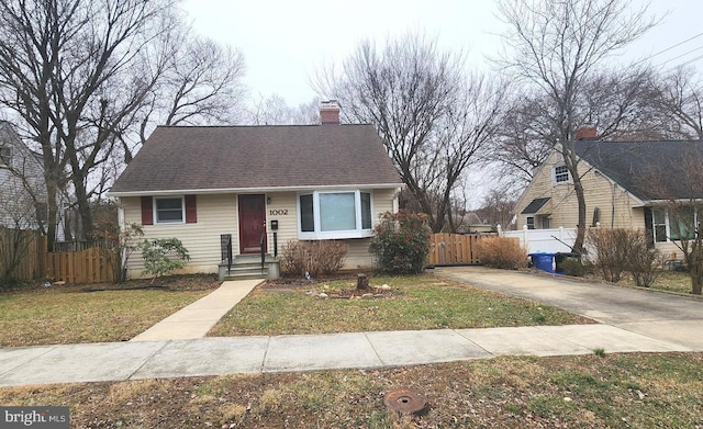 view of front of property with a chimney, fence, a front lawn, and roof with shingles