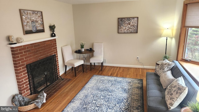 living room featuring a fireplace, baseboards, and wood finished floors