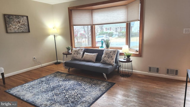 sitting room with wood-type flooring, visible vents, and baseboards