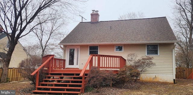 back of house with roof with shingles, fence, a chimney, and stairs