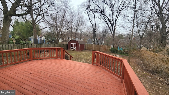 wooden terrace with a storage unit, an outdoor structure, and a fenced backyard